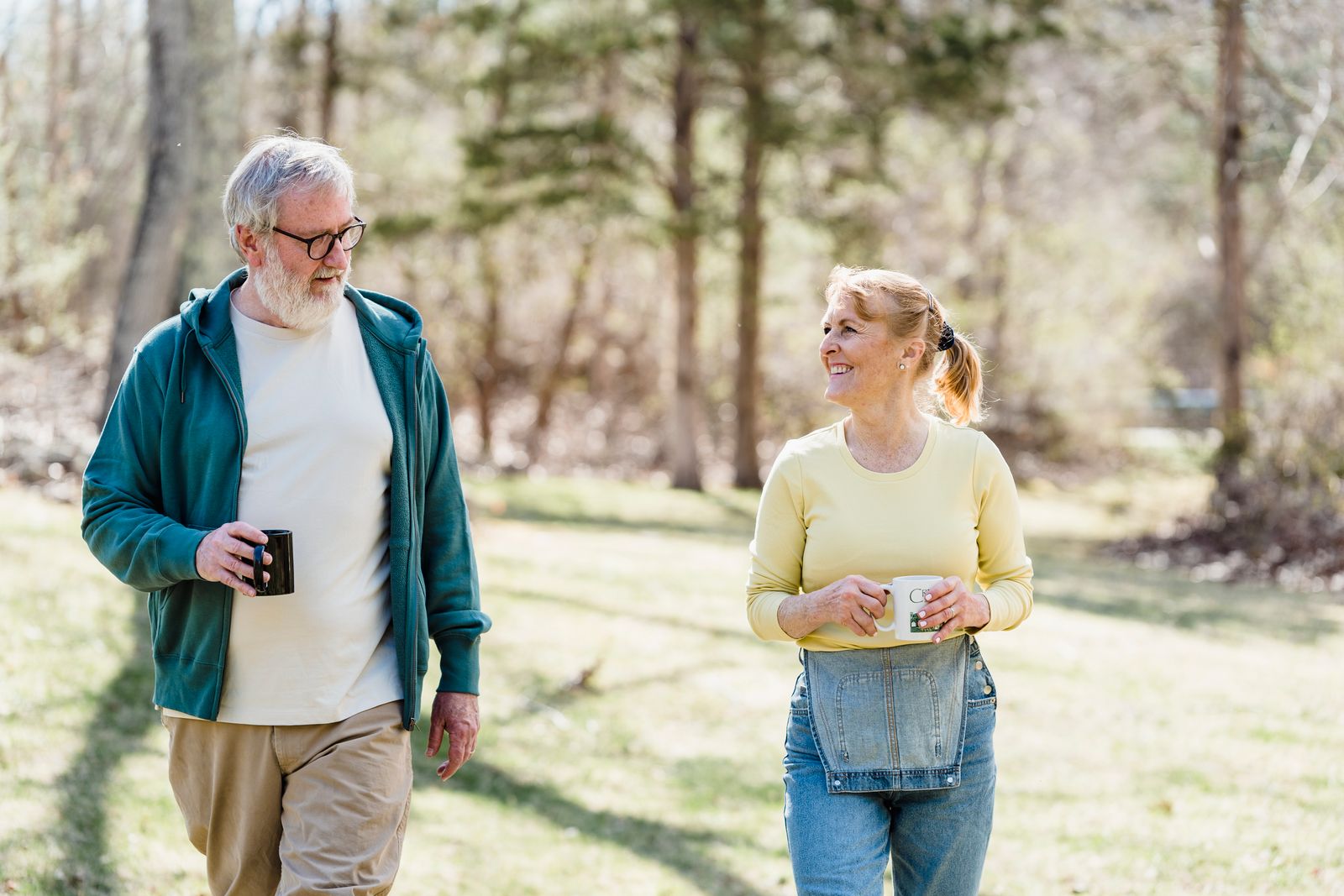 Happy elderly couple walking outdoors, sharing a joyful conversation with warm smiles.